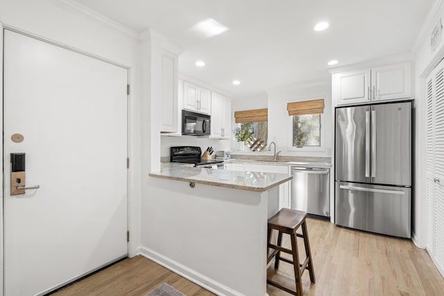 kitchen featuring sink, a kitchen breakfast bar, black appliances, white cabinets, and kitchen peninsula