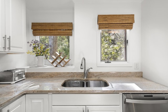 kitchen with sink, white cabinets, ornamental molding, stainless steel dishwasher, and light stone counters