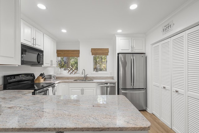 kitchen featuring stainless steel appliances, white cabinetry, light stone countertops, and sink