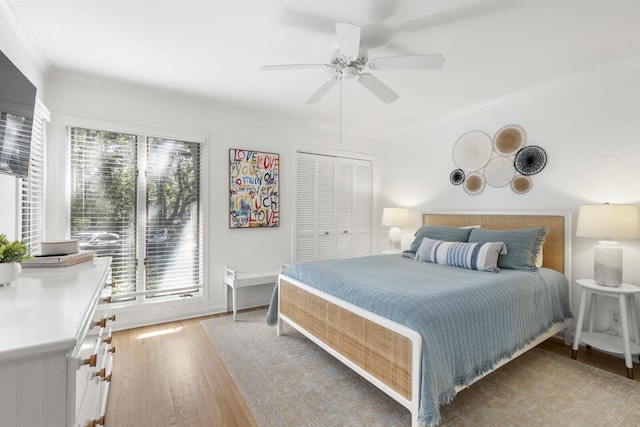 bedroom with hardwood / wood-style flooring, ceiling fan, ornamental molding, and a closet