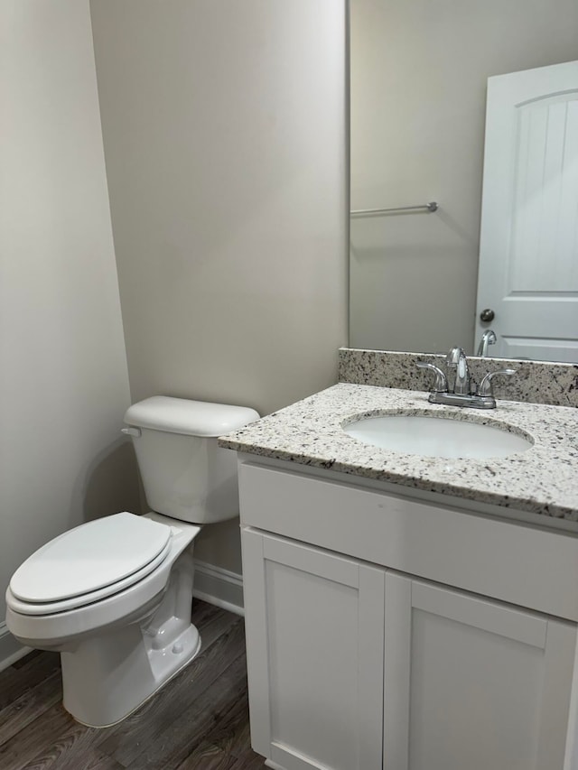 bathroom with toilet, vanity, and wood-type flooring