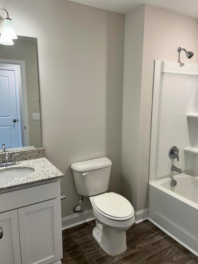 full bathroom featuring washtub / shower combination, hardwood / wood-style flooring, vanity, and toilet