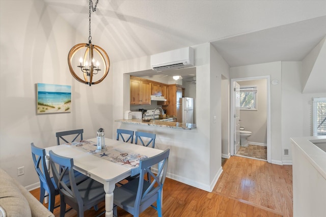 dining space featuring light hardwood / wood-style flooring, sink, and a wall mounted air conditioner