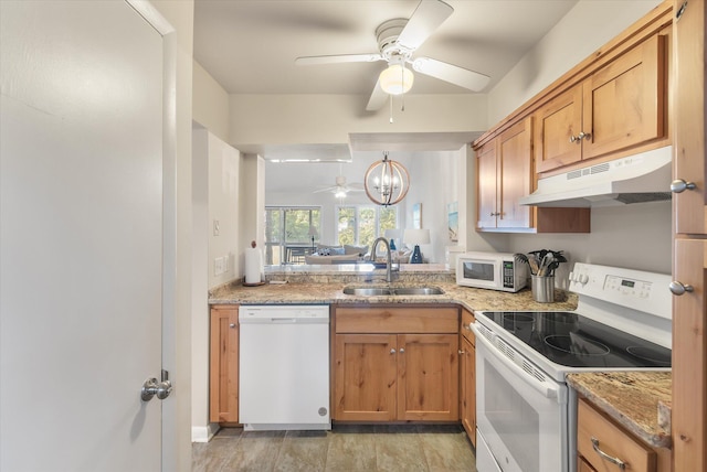 kitchen featuring decorative light fixtures, white appliances, light stone countertops, ceiling fan with notable chandelier, and sink