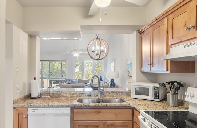 kitchen with ceiling fan with notable chandelier, sink, white appliances, and light stone counters