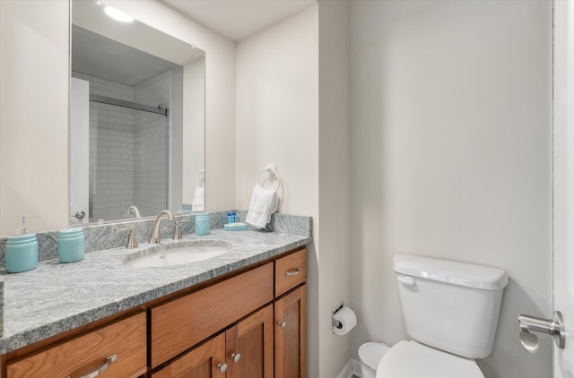 bathroom featuring toilet, vanity, and a shower with door