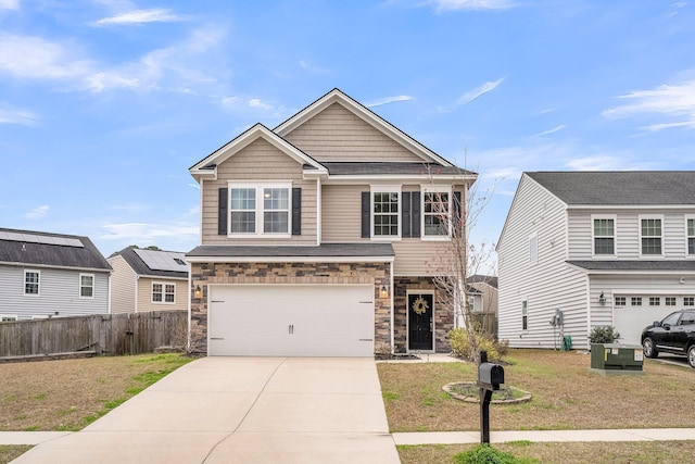 view of front of house with driveway, a garage, stone siding, fence, and a front yard