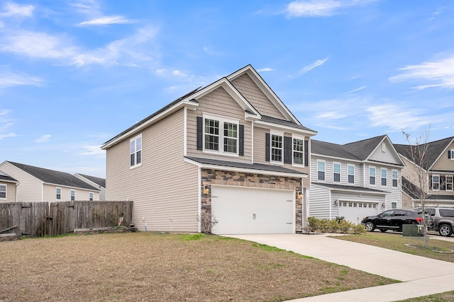 view of front of home featuring a front yard, stone siding, fence, and driveway