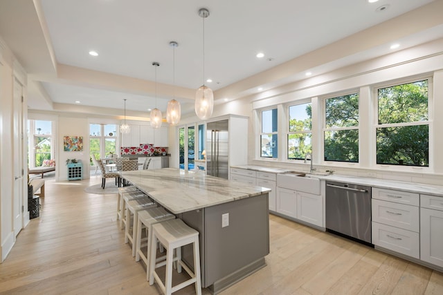 2213 Rolling Dune Rd, Seabrook Island, SC 29455 - kitchen featuring stainless steel appliances, light stone counters, a center island, a sink, and light wood finished floors