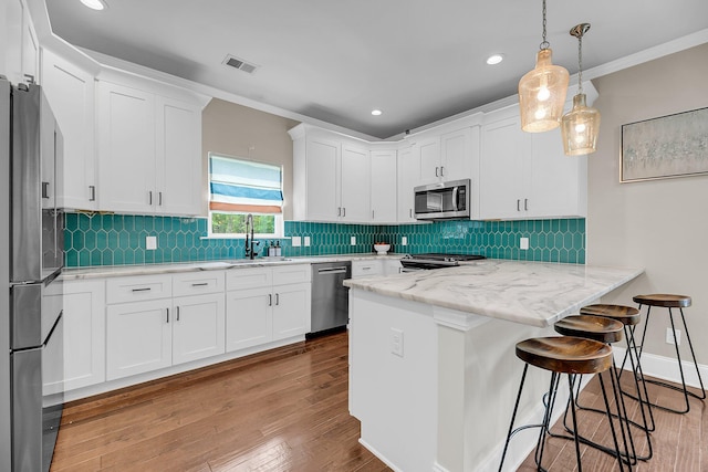 5725 Caviar Ct, Johns Island, SC 29455 - kitchen with appliances with stainless steel finishes, a sink, white cabinetry, a breakfast bar area, and wood finished floors