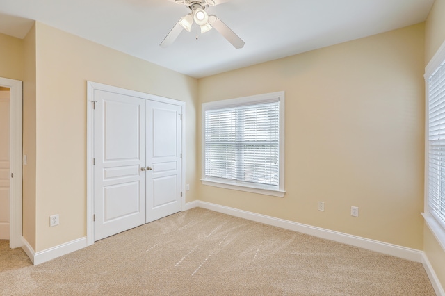 unfurnished bedroom with ceiling fan, a closet, and light carpet