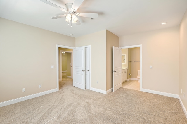 unfurnished bedroom featuring ceiling fan, light colored carpet, and ensuite bath