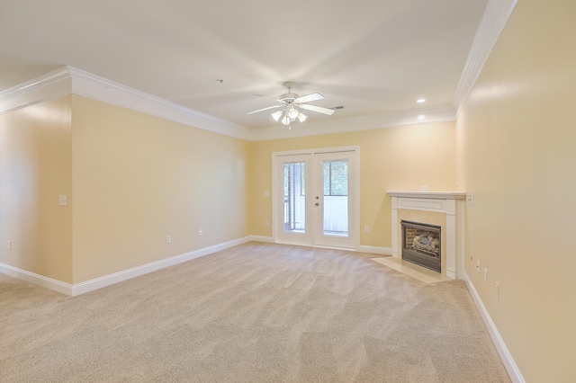 unfurnished living room with ceiling fan, crown molding, a tiled fireplace, and light carpet