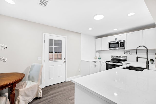 kitchen featuring stainless steel appliances, hardwood / wood-style floors, sink, and white cabinetry