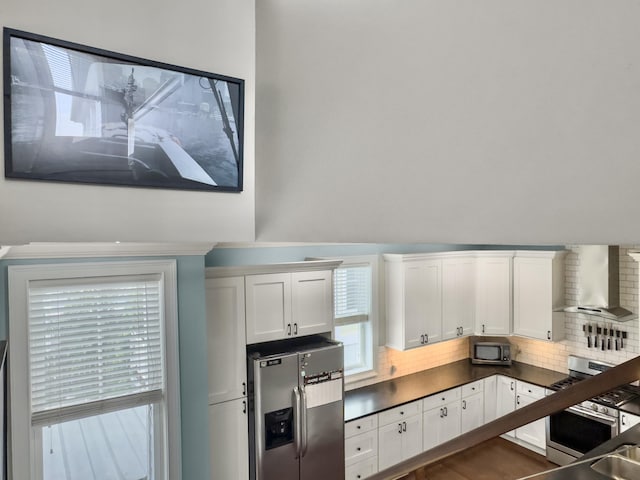 4 Line St, Charleston, SC 29403 - kitchen with wall chimney range hood, appliances with stainless steel finishes, backsplash, white cabinets, and dark countertops