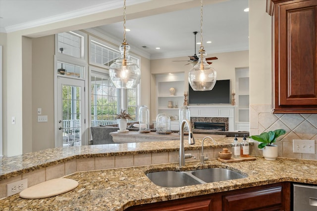 kitchen with light stone counters, crown molding, decorative backsplash, open floor plan, and a sink