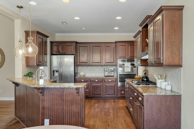 kitchen featuring dark wood-style floors, appliances with stainless steel finishes, a kitchen breakfast bar, a peninsula, and light stone countertops