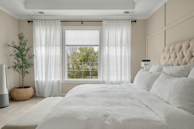 carpeted bedroom featuring ornamental molding, a raised ceiling, and visible vents