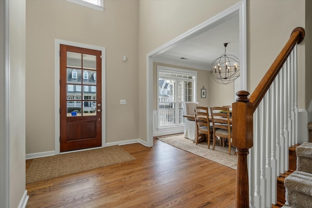 entryway with a notable chandelier, baseboards, stairway, and wood finished floors