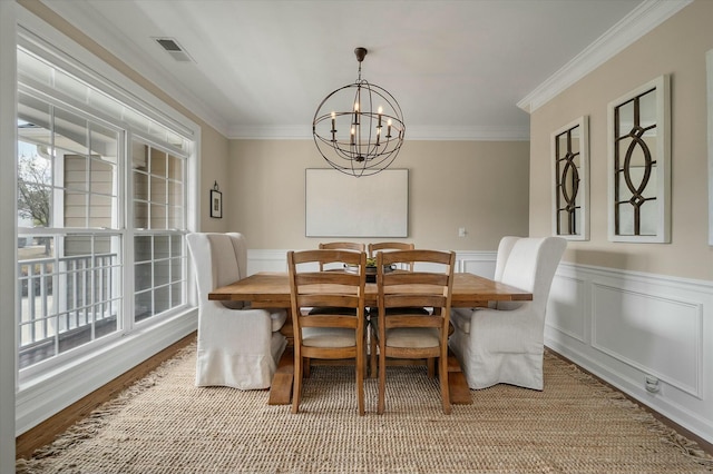 dining area with visible vents, wainscoting, ornamental molding, wood finished floors, and a chandelier