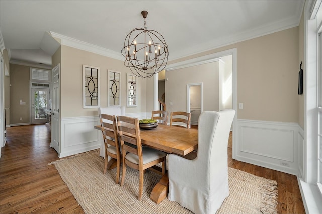 dining space with crown molding, a wainscoted wall, a notable chandelier, and wood finished floors