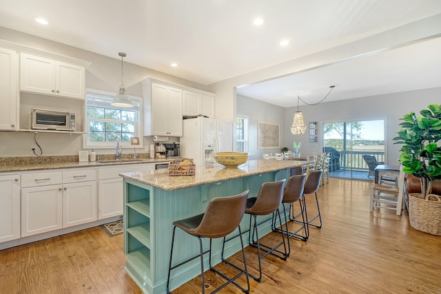 kitchen featuring sink, white cabinetry, hanging light fixtures, a kitchen island, and white refrigerator with ice dispenser