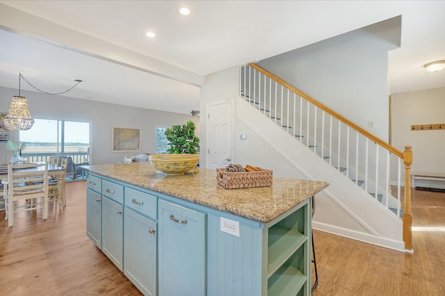 kitchen featuring light hardwood / wood-style flooring, baseboard heating, hanging light fixtures, a center island, and light stone countertops