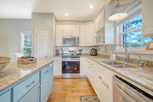 kitchen featuring pendant lighting, white cabinetry, stainless steel appliances, and sink