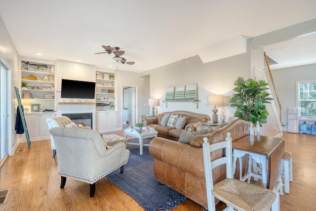 living room with ceiling fan, light wood-type flooring, and built in shelves