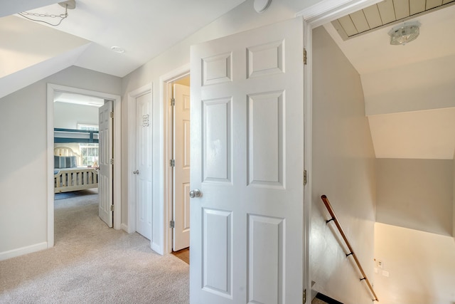 corridor with lofted ceiling and light colored carpet