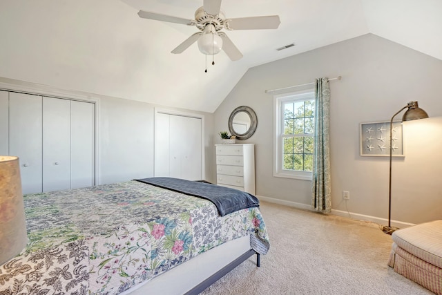 bedroom featuring lofted ceiling, ceiling fan, light colored carpet, and multiple closets