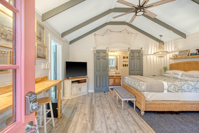 bedroom with vaulted ceiling with beams, wood-type flooring, and a barn door