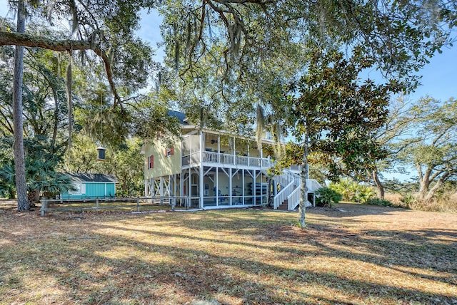 rear view of property featuring a lawn and a sunroom