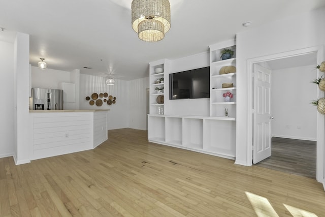 unfurnished living room with light wood finished floors and an inviting chandelier