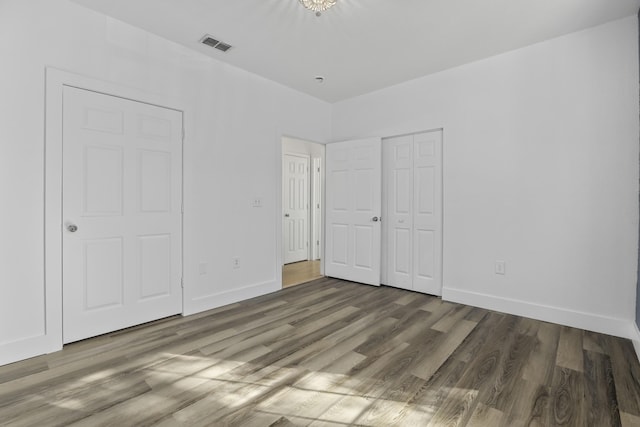 unfurnished bedroom featuring a closet, dark wood-style flooring, visible vents, and baseboards