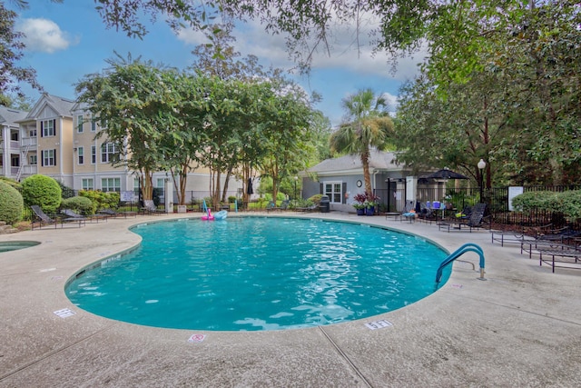 community pool with a patio area and fence