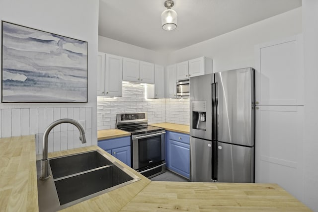 kitchen with stainless steel appliances, a sink, white cabinets, wooden counters, and decorative backsplash