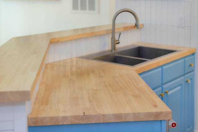 kitchen with blue cabinets, light countertops, a sink, and backsplash