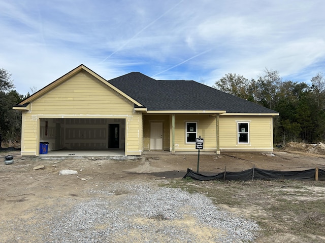 unfinished property with roof with shingles, an attached garage, and dirt driveway