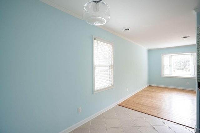 unfurnished room featuring baseboards, light tile patterned flooring, visible vents, and crown molding