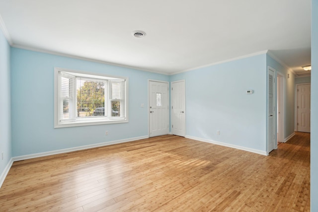 empty room with baseboards, crown molding, visible vents, and light wood finished floors