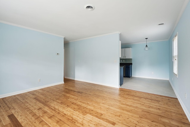 unfurnished room with light wood-style flooring, crown molding, visible vents, and baseboards