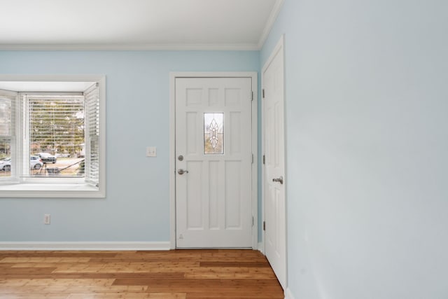 entrance foyer with ornamental molding, light wood-type flooring, and baseboards