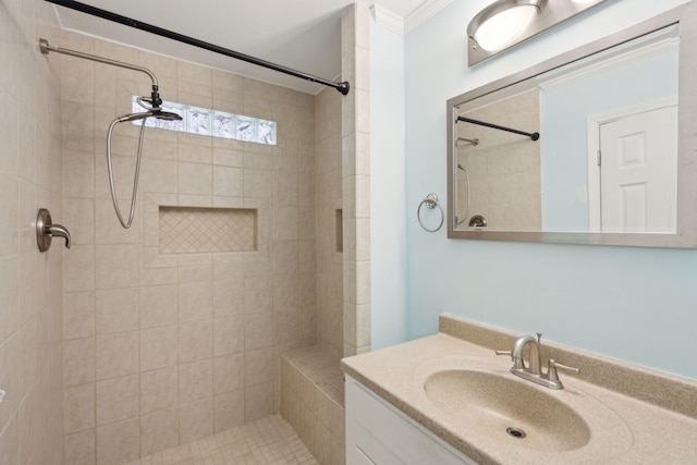 full bath with a tile shower, vanity, and crown molding