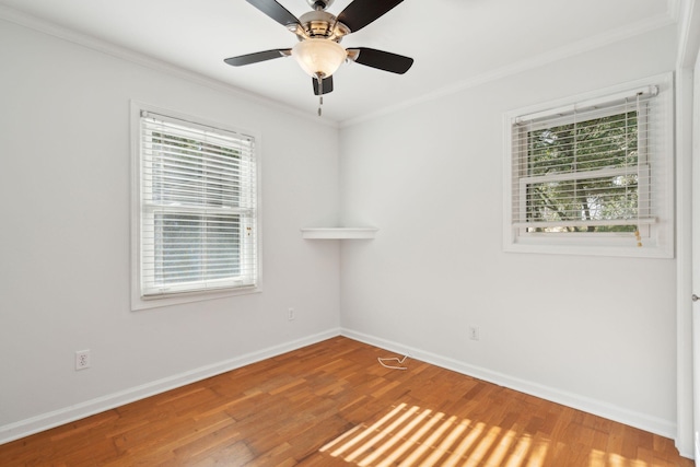 spare room featuring baseboards, wood finished floors, a wealth of natural light, and crown molding