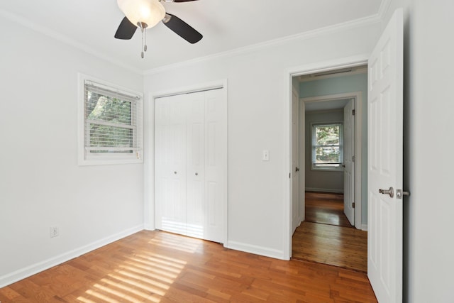 unfurnished bedroom featuring ornamental molding, a closet, wood finished floors, and baseboards