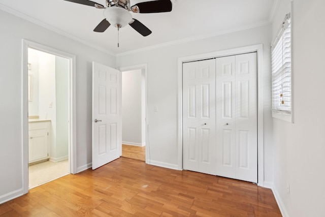 unfurnished bedroom with ceiling fan, baseboards, light wood-style floors, ornamental molding, and a closet