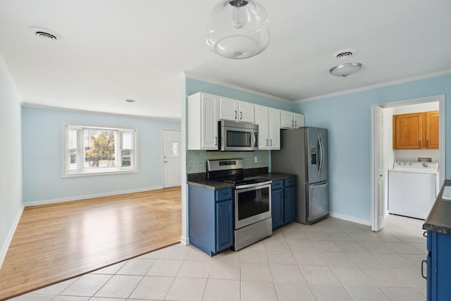 kitchen with washer / clothes dryer, white cabinetry, appliances with stainless steel finishes, tasteful backsplash, and dark countertops