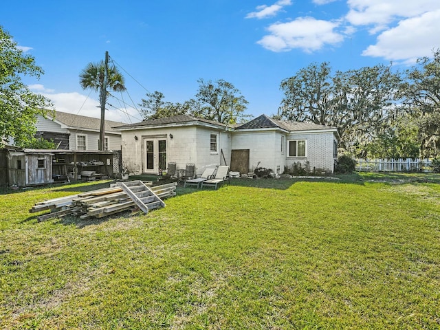 rear view of house with french doors and a lawn