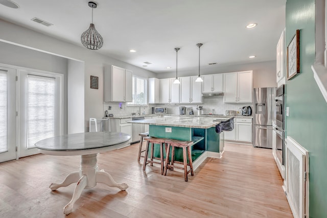 kitchen featuring plenty of natural light, a center island, stainless steel appliances, and decorative light fixtures